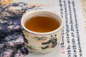 Jasmine Silver Needle tea served in a decorative panda cup against a traditional Chinese backdrop.