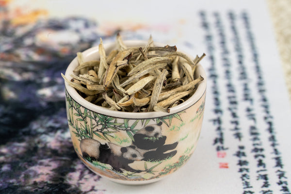 Jasmine Silver Needle tea leaves in a decorative panda cup, showcasing the ultra-rare, exquisite tea blend.